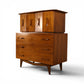 Young Manufacturing sculptural walnut highboy dresser angled view showing bowtie cutout pulls and curved stretcher base