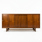 Cavalier Furniture MCM walnut lowboy dresser, straight-on front view with all four sliding door panels closed showing continuous grain and round brass pulls, c. 1960s