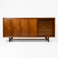 Cavalier Furniture MCM walnut lowboy dresser, right panel slid open revealing 3 drawers with brass bar pulls alongside two closed door panels on left, c. 1960s